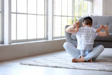 Küçük bebek annesinin yardımıyla evde yürümeyi öğreniyor.