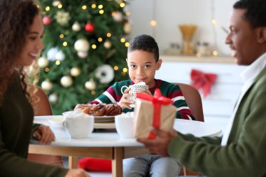 Koca, Noel arifesinde karısını evde karşılıyor.