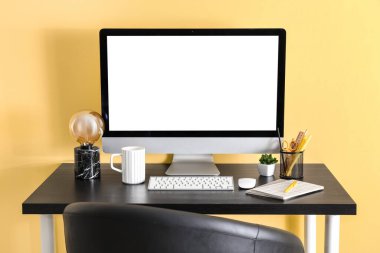 Modern bilgisayarı, kırtasiyesi, fincanı ve lambası olan rahat iş yeri renk duvarının yanında.