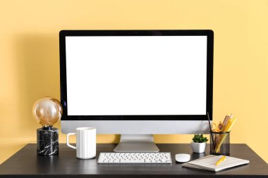 Modern bilgisayar, kırtasiye ve fincanla renkli duvarın yanında rahat bir iş yeri