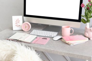 Modern bilgisayar, defterler ve fincanlar gri masada.