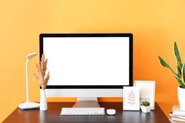 Renk duvarının yanında modern bilgisayar, lamba ve şık dekoru olan işyeri