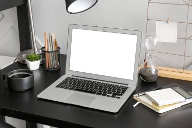 Modern laptop, kahve fincanı, defter ve hesap makinesi masada.