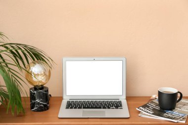 Modern dizüstü bilgisayar, lamba, bardak ve dergiler renk duvarının yanında.