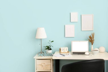 Modern dizüstü bilgisayarı, cep telefonu, kulaklığı ve renkli duvarın yanında çay fincanı olan rahat bir iş yeri.