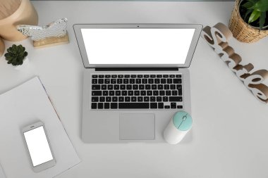 Modern laptop, bilgisayar faresi ve cep telefonu ışık masasında