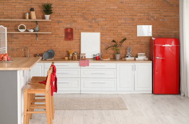 Modern mutfak, yemek masası, tezgah ve şık buzdolabı.