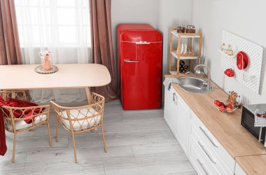 İçinde retro buzdolabı, beyaz tezgah ve yemek masası olan aydınlık mutfak.