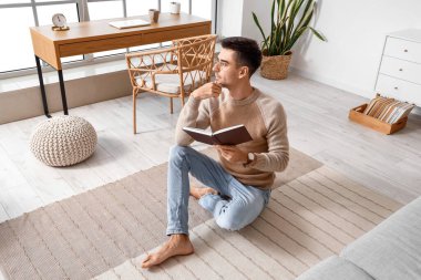 Evde kitap okuyan yalınayak genç adam.