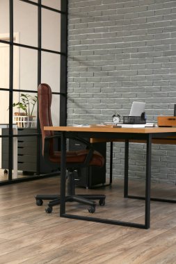 Ofisin içindeki gri tuğla duvarın yanında rahat bir iş yeri.
