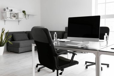 Konferans odasında bilgisayar ve su şişeleriyle dolu bir masa.