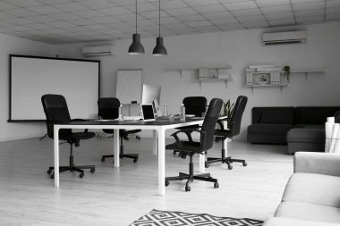 Konferans salonunun içi büyük masa ve modern bilgisayarlarla dolu.