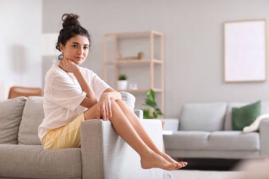 Evdeki kanepede oturan güzel çıplak ayaklı kadın.