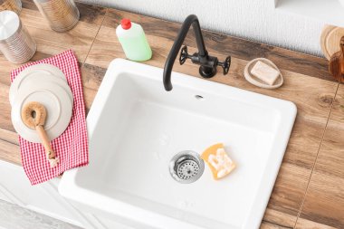 Temiz bulaşık takımlarıyla ahşap tezgah ve lavaboda köpükle sünger.