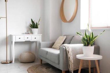 Oturma odasındaki beyaz duvarın yanında çiçekli kanepe ve masalar