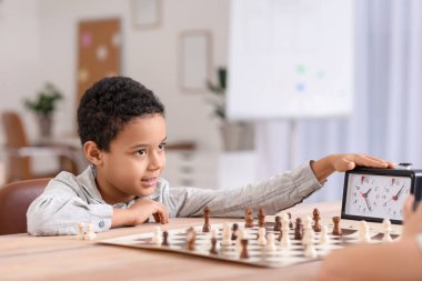 Kulüpte turnuvada satranç oynayan küçük Afro-Amerikalı çocuk.