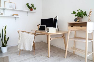 Beyaz duvarın yanında modern monitörlü ve dizüstü bilgisayarlı bir işyeri