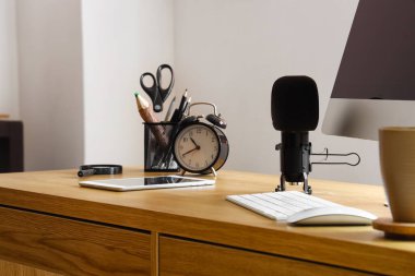 Tablet bilgisayar, mikrofon ve alarmlı saat masada.