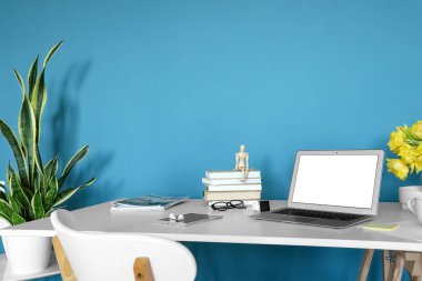 Modern aletler, kitaplar ve dergiler mavi duvarın yanında.