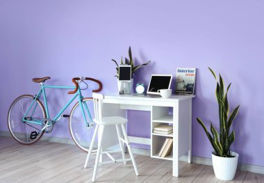 Rahat bir iş yeri ve odanın içindeki renkli duvarın yanında bisiklet.