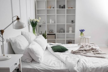 Vazolarda çiçekler olan modern yatak odasının içi.