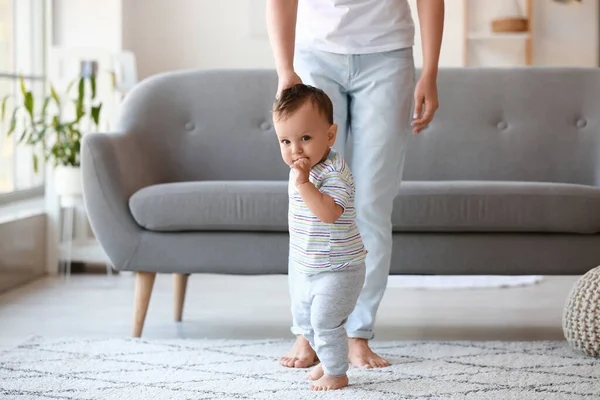 Küçük bebek annesinin yardımıyla evde yürümeyi öğreniyor.