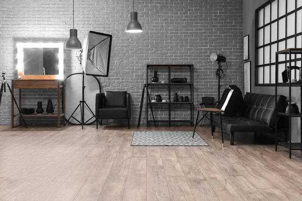 Rafların, aynanın ve profesyonel ekipmanların bulunduğu modern fotoğraf stüdyosunun içi