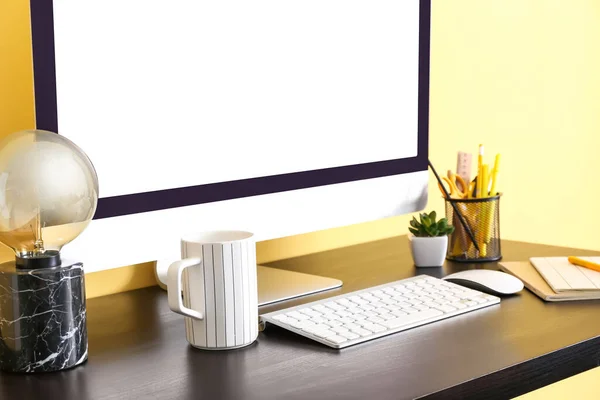 彩色墙边桌上的现代电脑 杯子和文具 — 图库照片