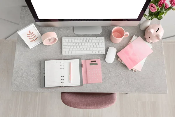 Computer, notebooks, alarm clock, piggy bank and cup on grey table