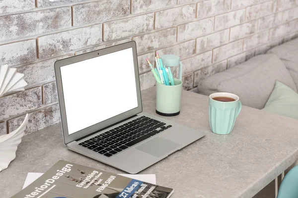 Modern Laptop Tidningar Och Kopp Bordet Nära Ljus Tegelvägg — Stockfoto