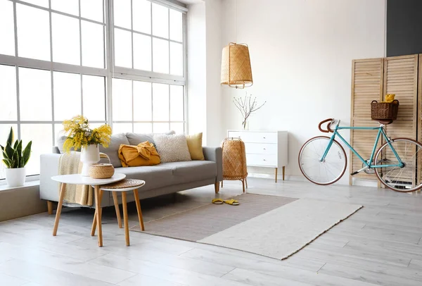 Modern oturma odasının içinde vazo ve kanepede mimoza çiçekleri var.