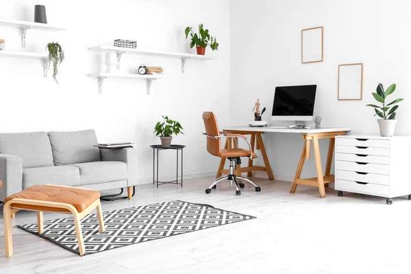 快適なソファと客室内の白い壁の近くの現代的なコンピュータと職場 — ストック写真