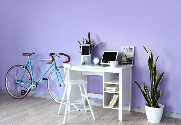 Rahat bir iş yeri ve odanın içindeki renkli duvarın yanında bisiklet.
