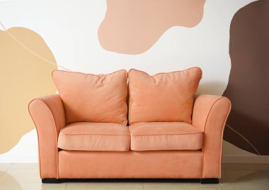 Oturma odasındaki renkli duvarın yanındaki şık kanepe.