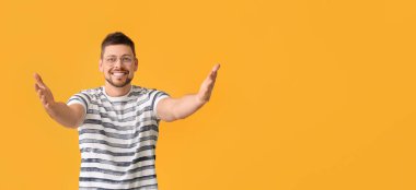 Turuncu arka planda sarılmak için kollarını açan mutlu bir adam.