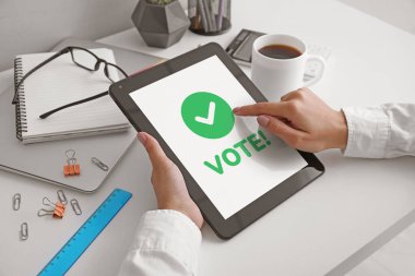 Tablet bilgisayarlı genç bir kadın ofiste oylama yapıyor.