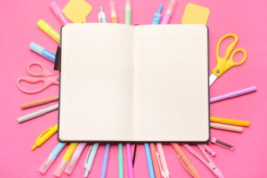 Pembe zemin üzerinde boş defter ve kırtasiye malzemesi olan kompozisyon