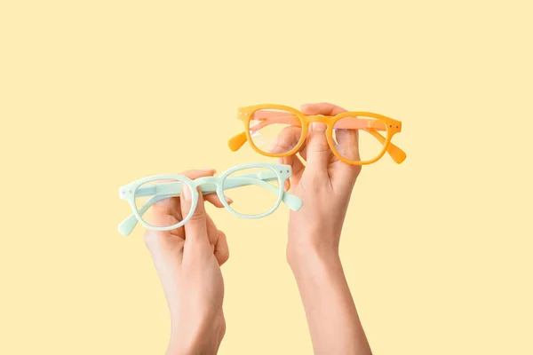 Mãos Femininas Com Óculos Diferentes Fundo Amarelo — Fotografia de Stock