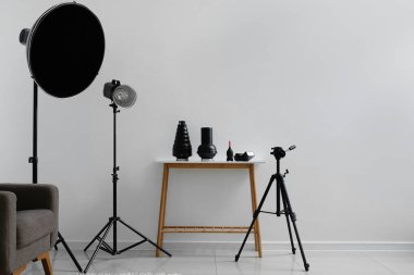 Fotoğraf stüdyosunun içinde ışık duvarı yakınında farklı modern ekipmanlara sahip bir masa.