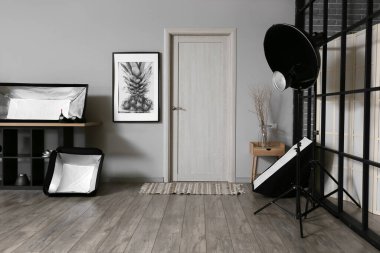 Duvar kenarındaki farklı modern ekipmanlar şık bir fotoğraf stüdyosunun içinde.