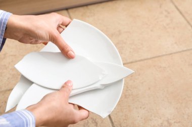 Kırık tabak parçalarıyla kadın elleri. Renkli fayanslar, yakın plan.