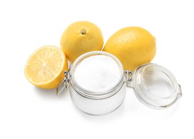 Beyaz arka planda kabartma tozu ve olgun limonlarla dolu cam kavanoz.