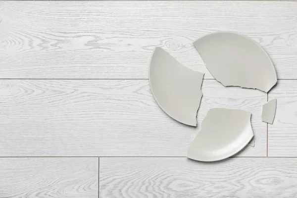 Açık ahşap zemin üzerinde kırık seramik tabak