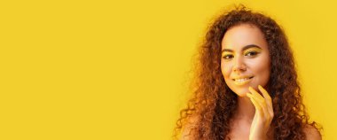 Turuncu arka planda sarı tonlarda makyajlı güzel bir Afro-Amerikalı kadın.