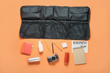 Black travel organizer with different things and bottle of drink on color background