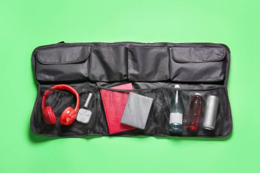 Travel organizer with different things and bottles of drink on green background