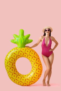 Pembe arka planda şişirilebilir yüzüğü olan çekici genç bir kadın.