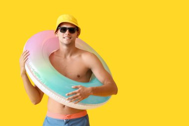 Sarı arka planda şişme yüzüğü olan çekici bir genç adam.