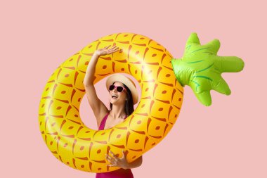 Pembe arka planda şişme yüzüğü olan mutlu genç bir kadın.