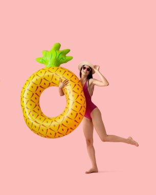 Pembe arka planda şişirilebilir yüzüğü olan çekici genç bir kadın.